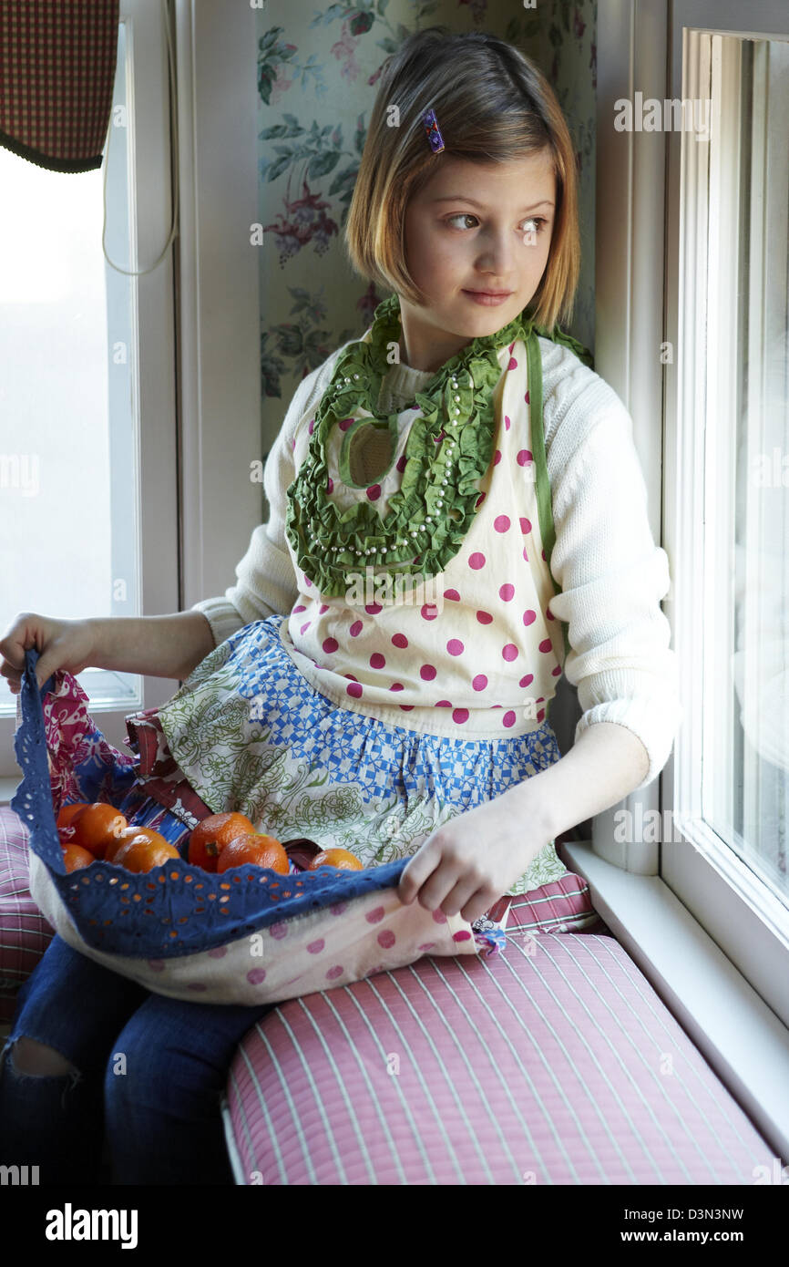 8 anno vecchia ragazza tenendo le arance nel suo grembiule Foto Stock