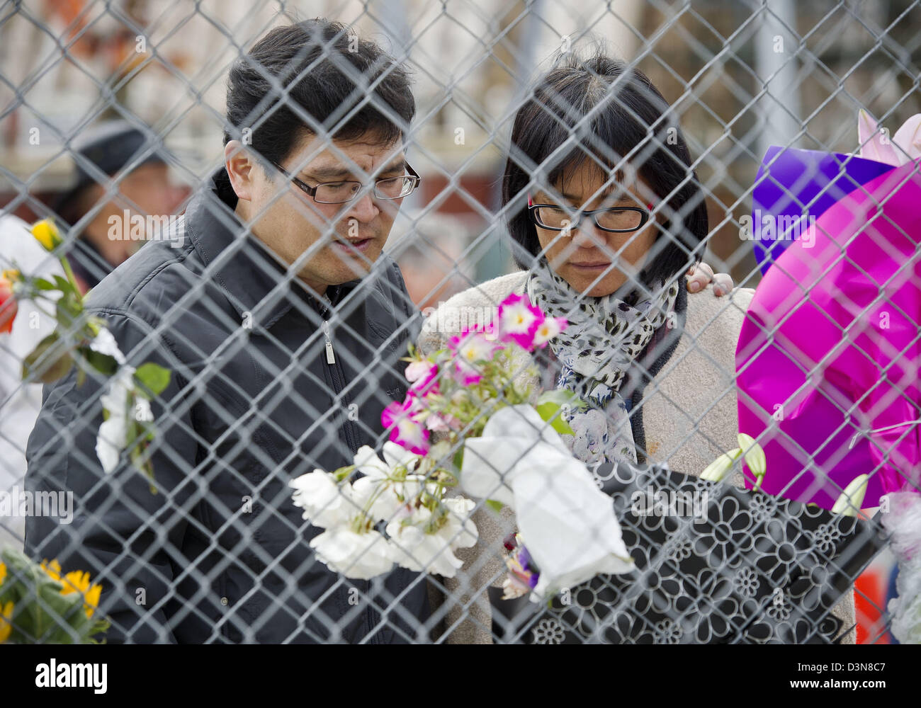 Febbraio 22, 2013 - Christchurch, Nuova Zelanda - un memoriale di servizio in occasione del secondo anniversario della Feb.22, 2011 terremoto che decimò Christchurch e sinistra 185 morti si è tenuto nella città del Latimer Square. Il servizio in primo piano le preghiere e gli inni, colloqui dal Primo Ministro John Key e il sindaco di Christchurch Bob Parker, una comunità fiore omaggio e un momento di silenzio a 12:51 p.m. il tempo che il sisma ha colpito. Ci sono state anche altre iniziative commemorative in tutta la città. Qui, un paio di dire una preghiera dopo l'immissione di fiori su una catena collegamento recinto presso l'ex CTV sito di costruzione. (Credito Immagine: © PJ H Foto Stock