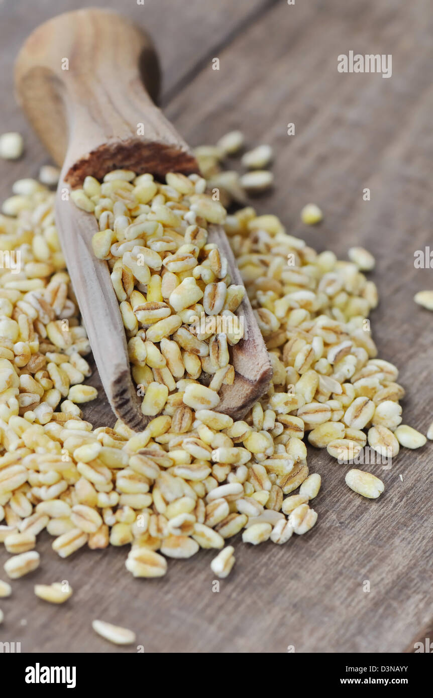 Chicchi di grano in un cucchiaio su uno sfondo di legno Foto Stock