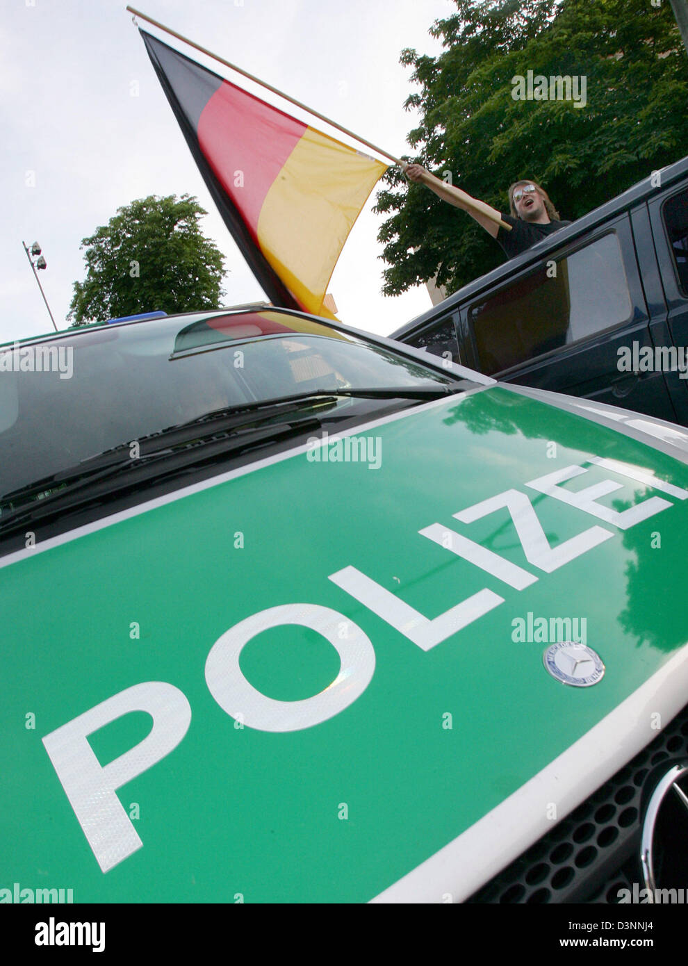 Una ventola sventola una bandiera tedesca nella parte anteriore di una macchina della polizia in una sfilata di auto a Friburgo in Germania, venerdì 9 giugno 2006. I tifosi hanno celebrato la Germania la vittoria sulla Costa Rica in opneing partita della Coppa del Mondo 2006. Foto: Patrick Seeger Foto Stock