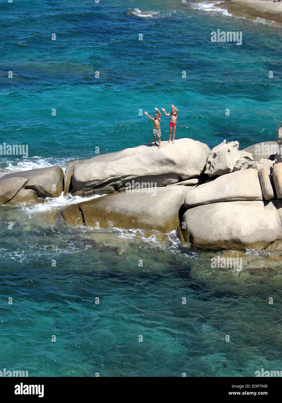 Due bambini di stare su una roccia e delle onde sulla costa orientale della Sardegna, Italia, 25 agosto 2006. Foto: Stephan Jansen Foto Stock