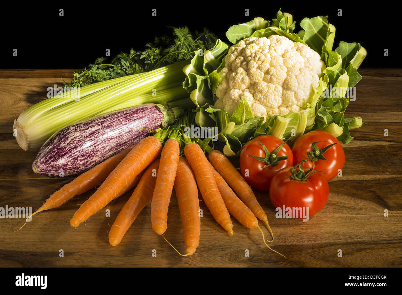 Verdure per la cottura con cavolfiore, carote, pomodori, sedano e melanzane  su un tavolo in legno e sfondo nero Foto stock - Alamy