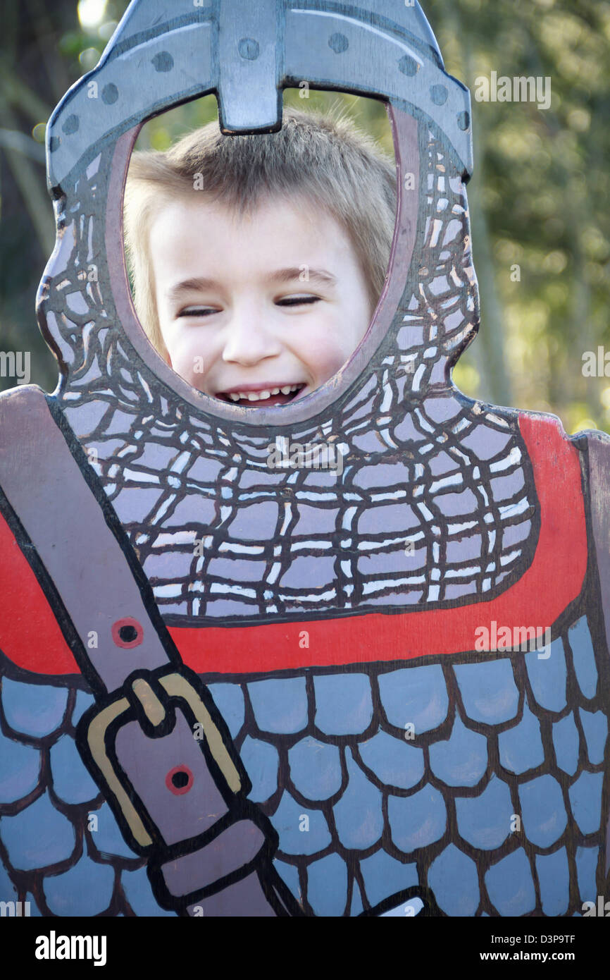 Ragazzo (6 anni) in posa dietro il cavaliere medievale ritaglio di cartone. Foto Stock