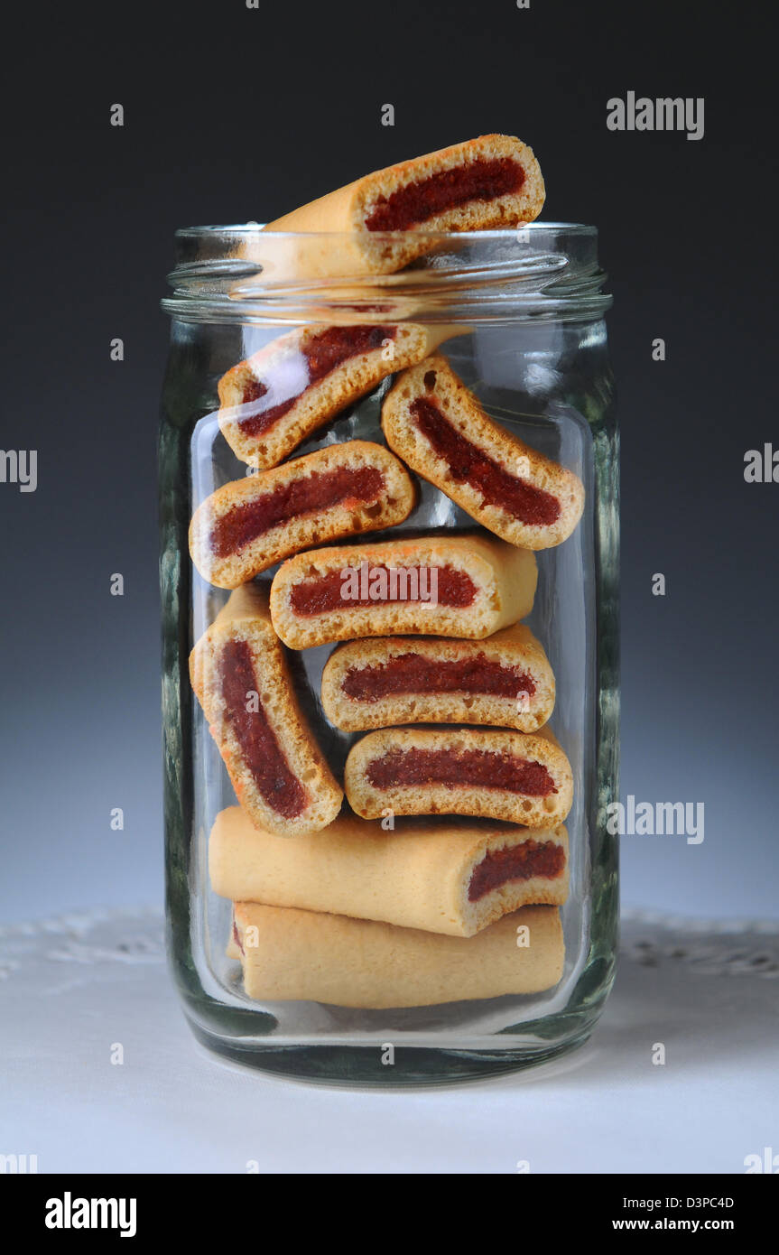 Primo piano di un vasetto di vetro pieno di frutta bar cookie. Formato verticale su una luce di sfondo grigio scuro. Foto Stock