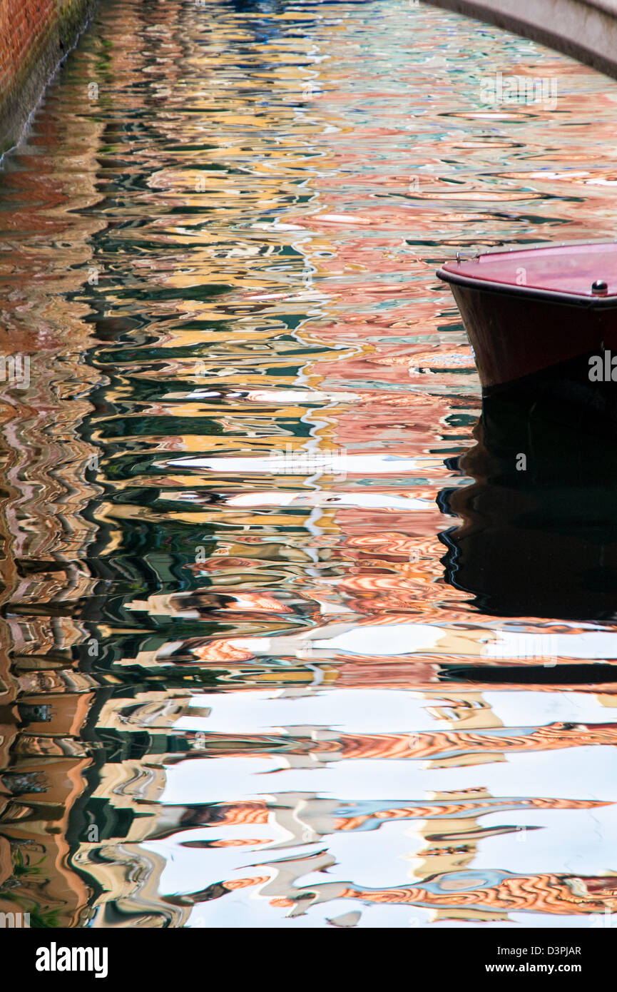 Barca in Canal con riflessi colorati di edifici a Venezia Foto Stock