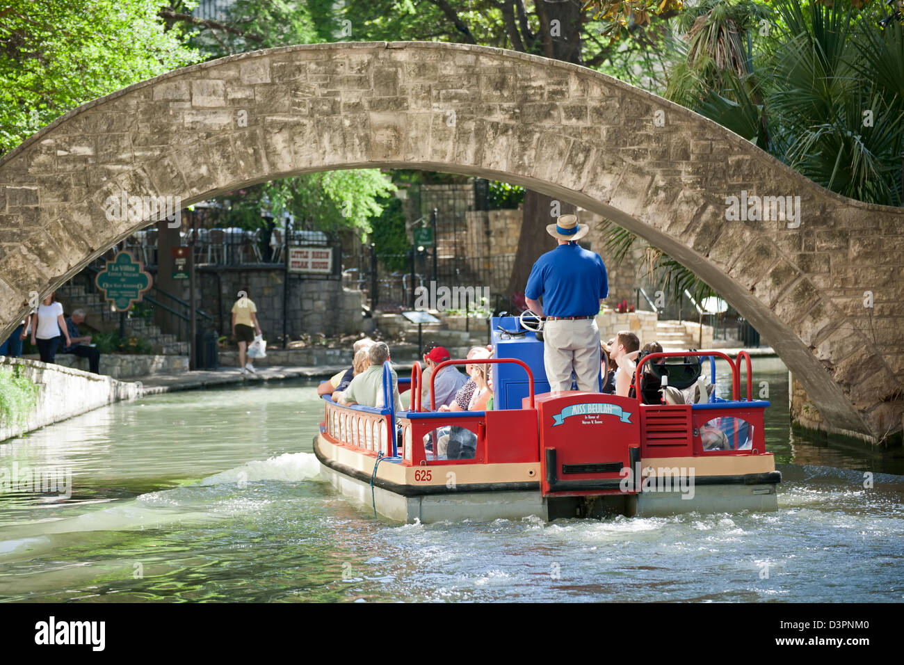Imbarcazione turistica passando sotto il ponte sul fiume San Antonio lungo il lungofiume di San Antonio, Texas, Stati Uniti d'America Foto Stock