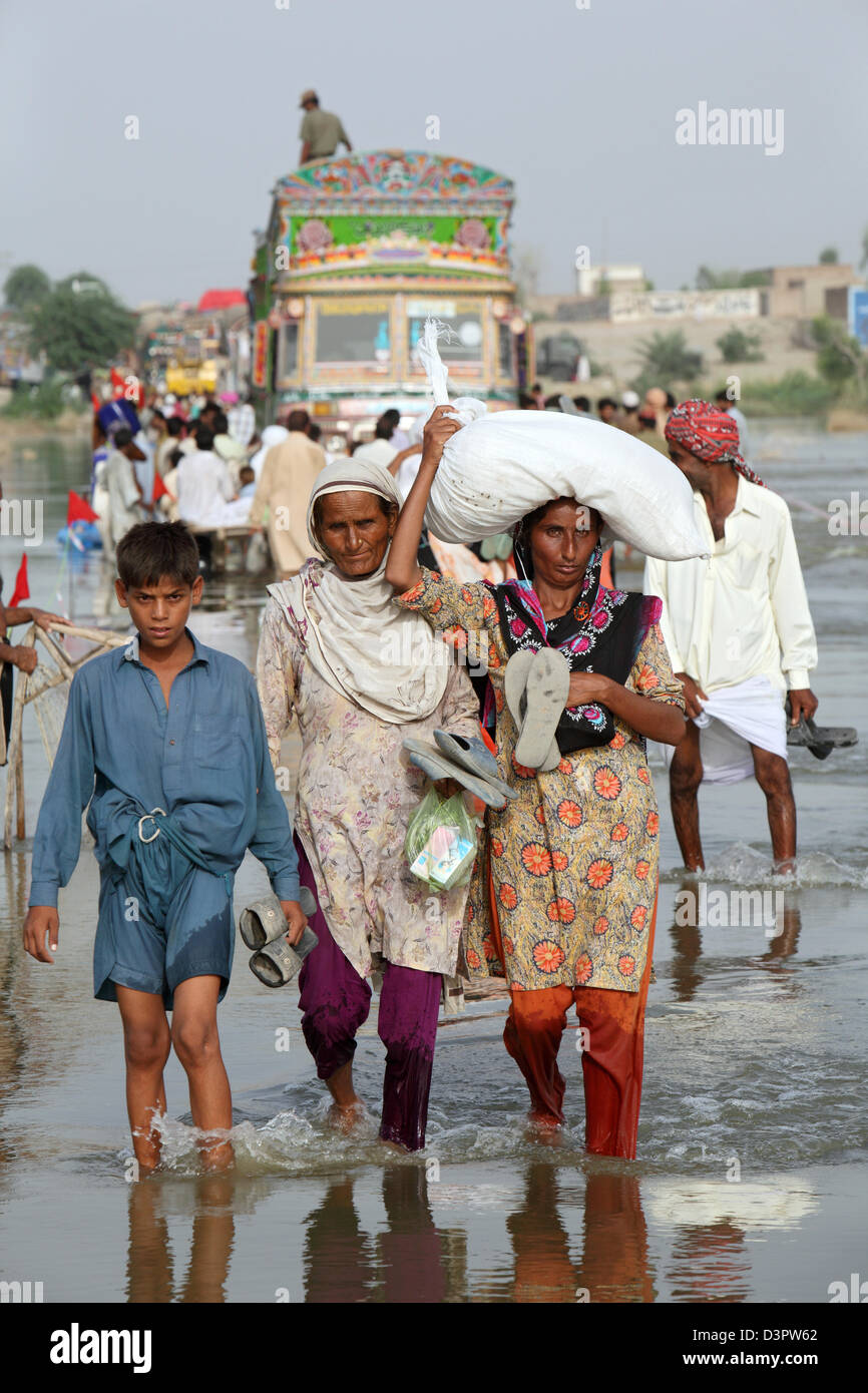 Muzaffargarh, Pakistan, persone wade attraverso strade inondate da Foto Stock
