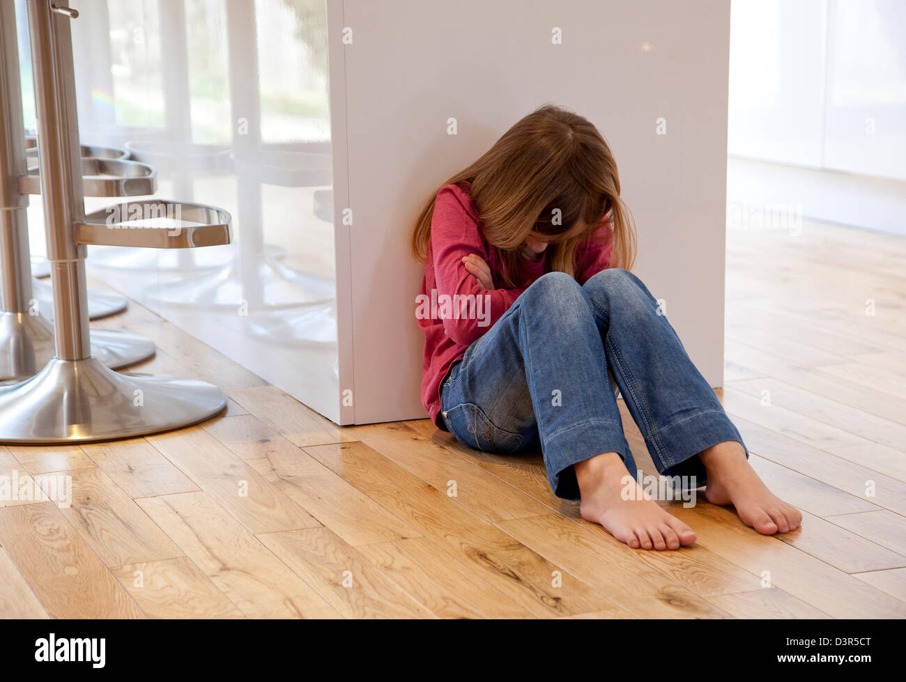 Giovane ragazza sedeva infelice sul pavimento Foto Stock
