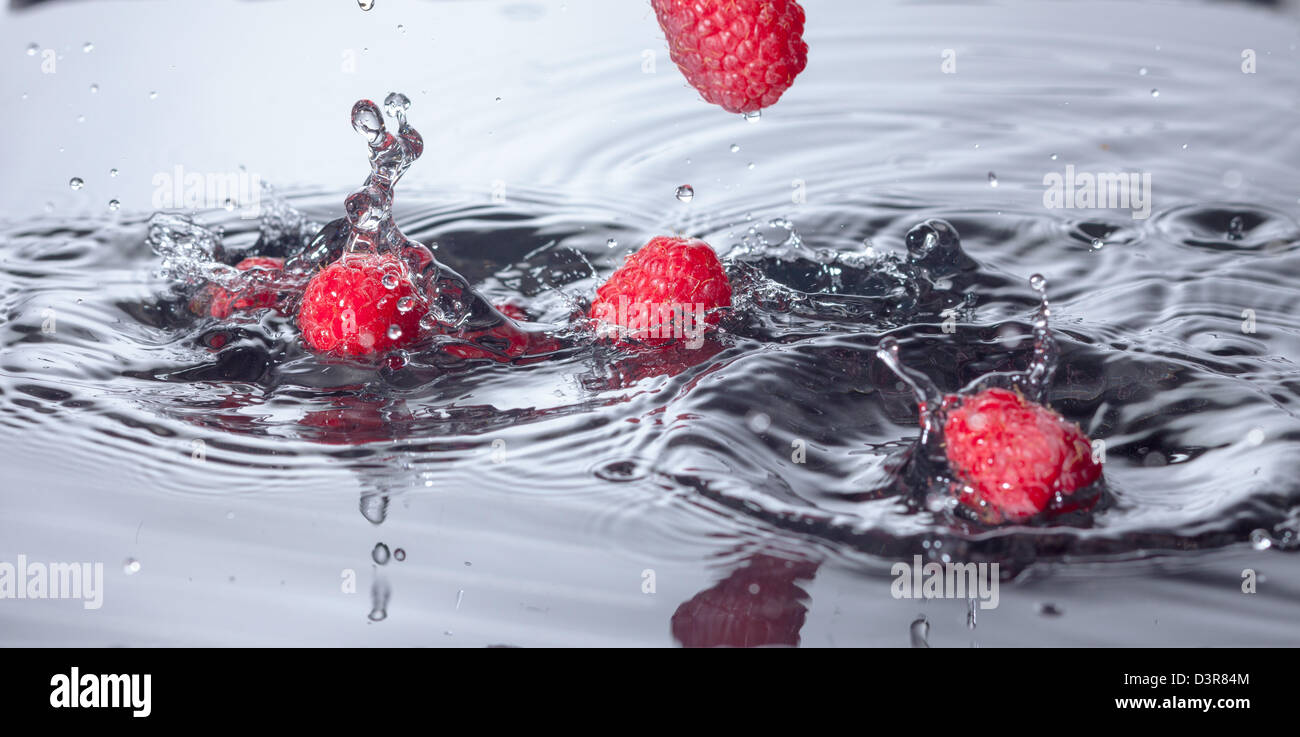 Il lampone rosso cade in acqua con Splash, primo piano Foto Stock