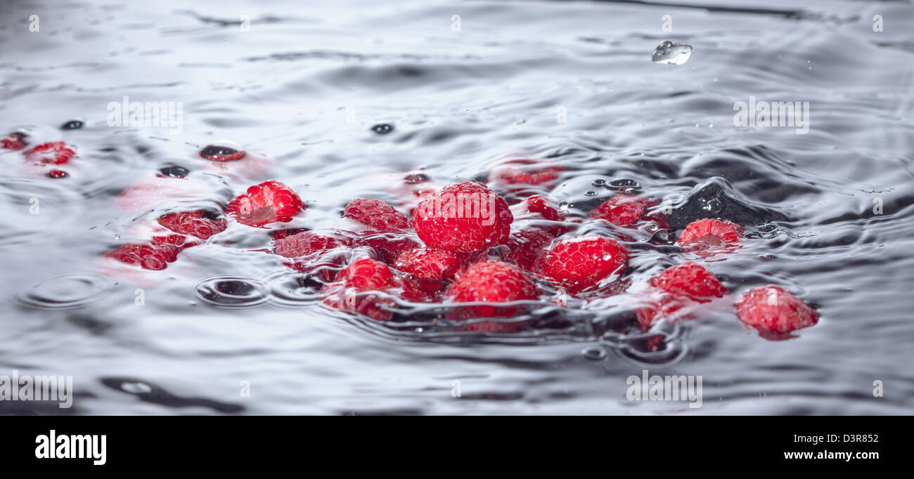 Il lampone rosso cade in acqua con Splash, primo piano Foto Stock