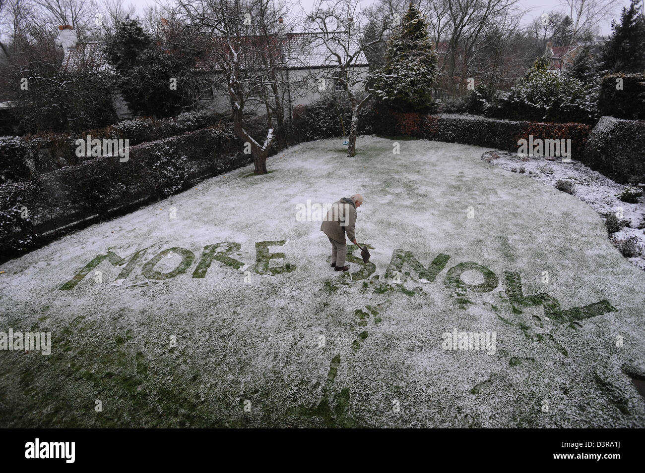 Anziani nonno scrivendo un messaggio umoristico più neve nella neve in giardino Foto Stock