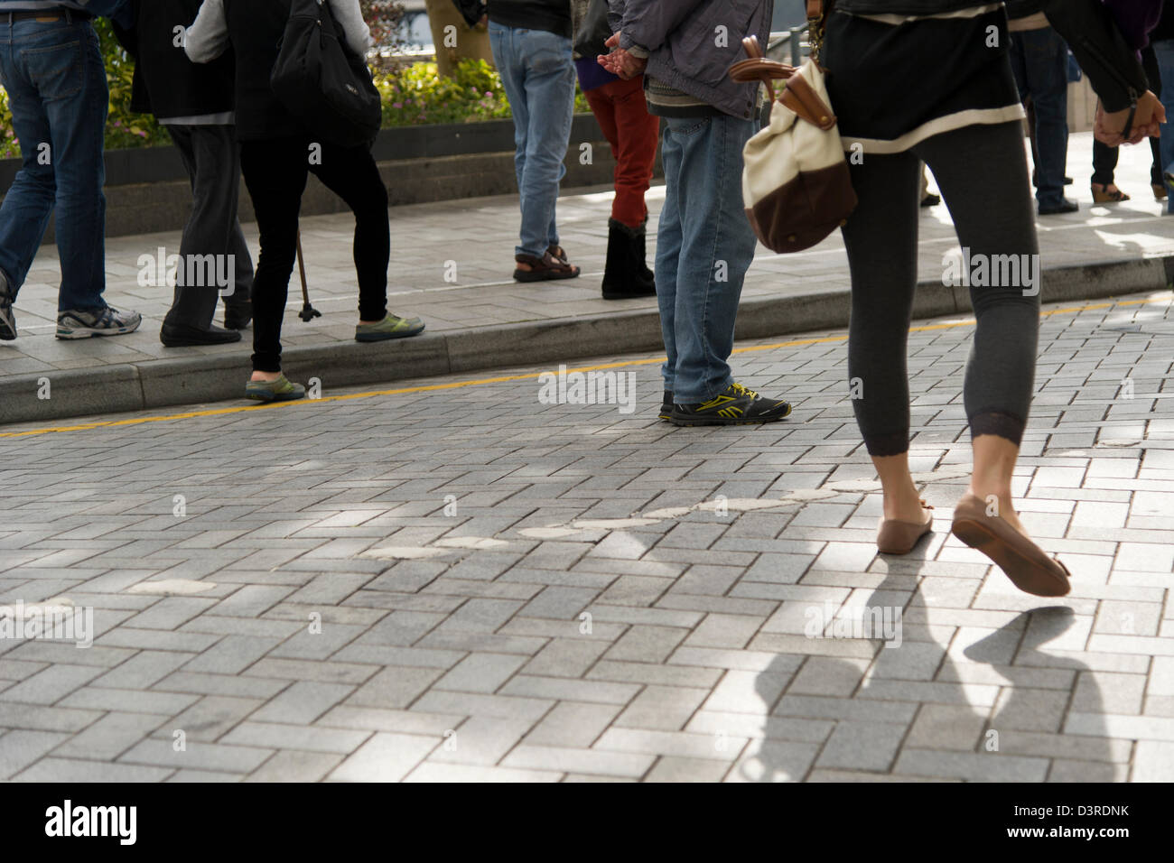 Le gambe e i piedi dei passanti sono visibili sul lungomare di Stanley in Hong Kong Foto Stock