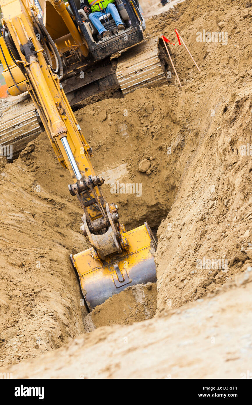 Di lavoro trattore escavatore scavare una trincea. Foto Stock