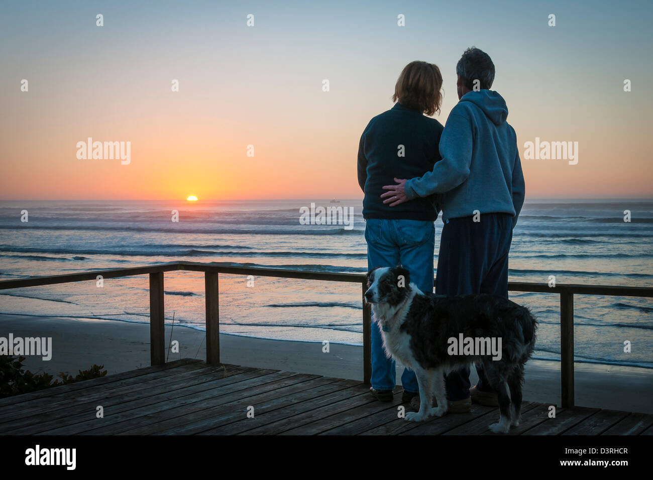 Giovane con cane guardando il tramonto sull'oceano da beach house a Yachats sulla centrale di Oregon Coast. Foto Stock