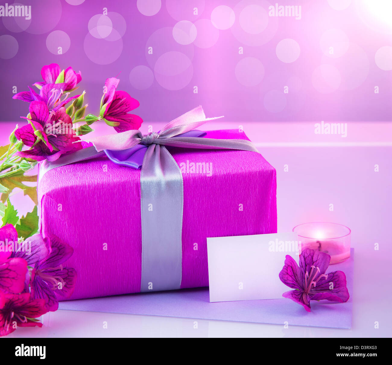 Foto di rosa elegante confezione regalo con bouquet di fiori belli, romantico ambiente a lume di candela e una cartolina con testo spazio sul tavolo Foto Stock