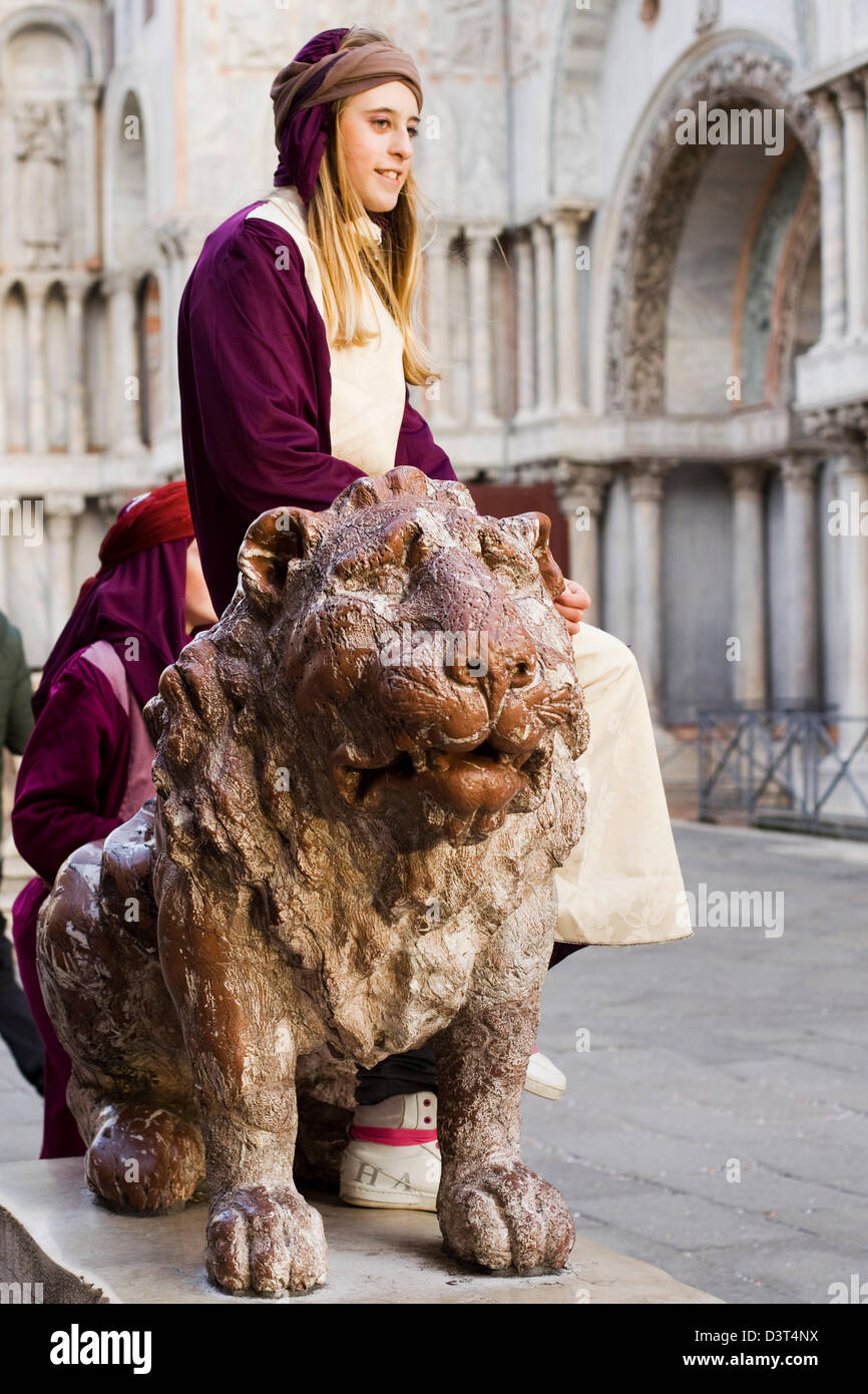 Ragazza sedeva su un bronzo dorato Leone in Piazza San Marco Venezia Italia Foto Stock