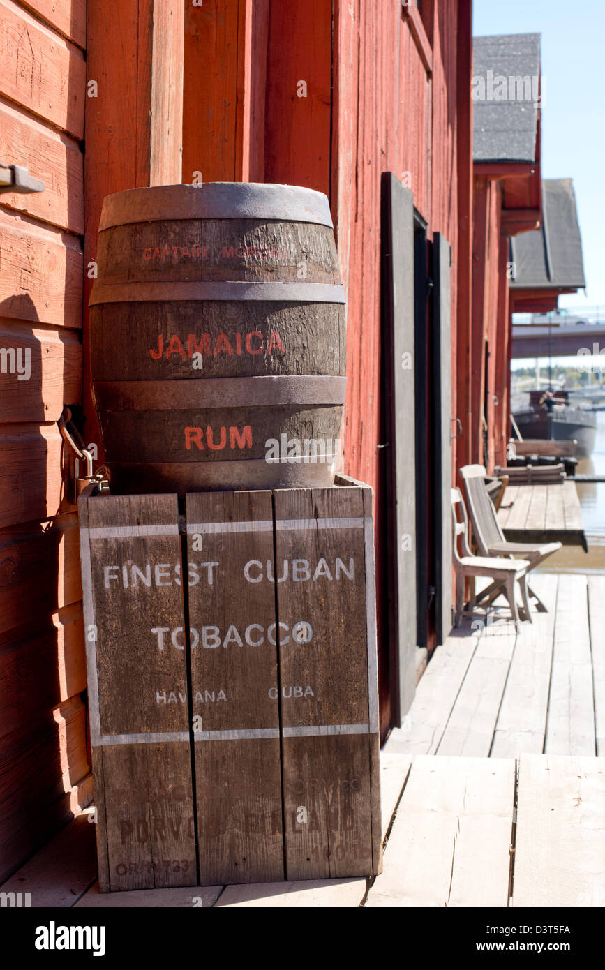 Barile di rum giamaicano impilati sulla parte superiore del torace di tabacco cubano di fronte un rosso casa in legno Foto Stock