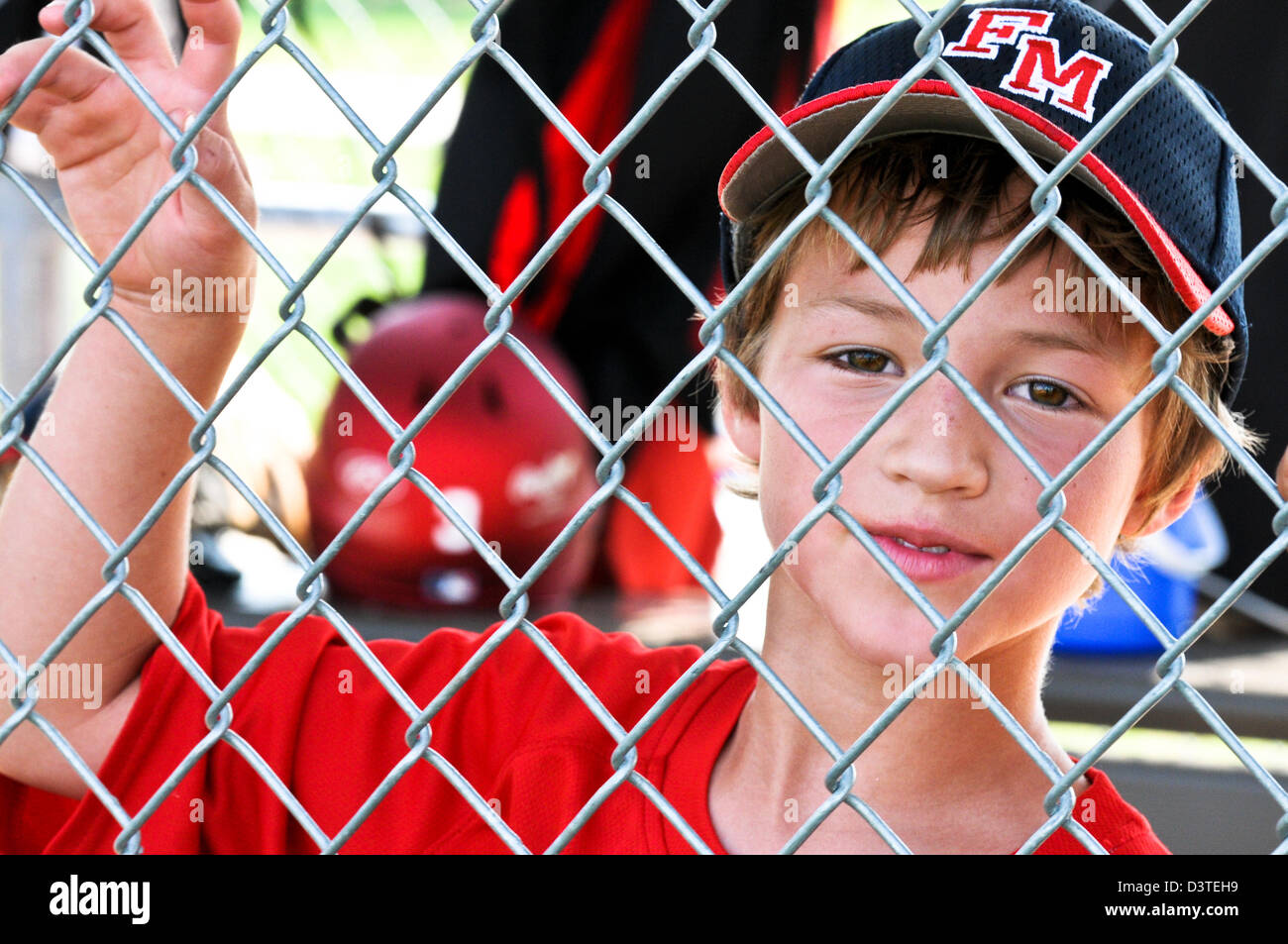 Da vicino il colpo di un po' di baseball della lega il giocatore in piedi in panchina dietro il recinto. Foto Stock