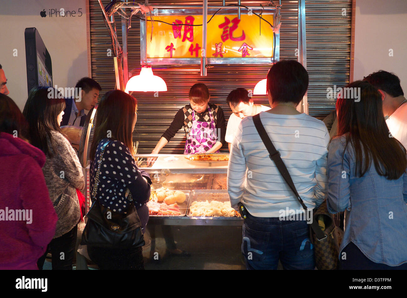 Venditore ambulante di vendita del pesce di sfere e altre prelibatezze in tarda notte, Macau SAR la Cina con una folla di persone raccolte intorno a Foto Stock