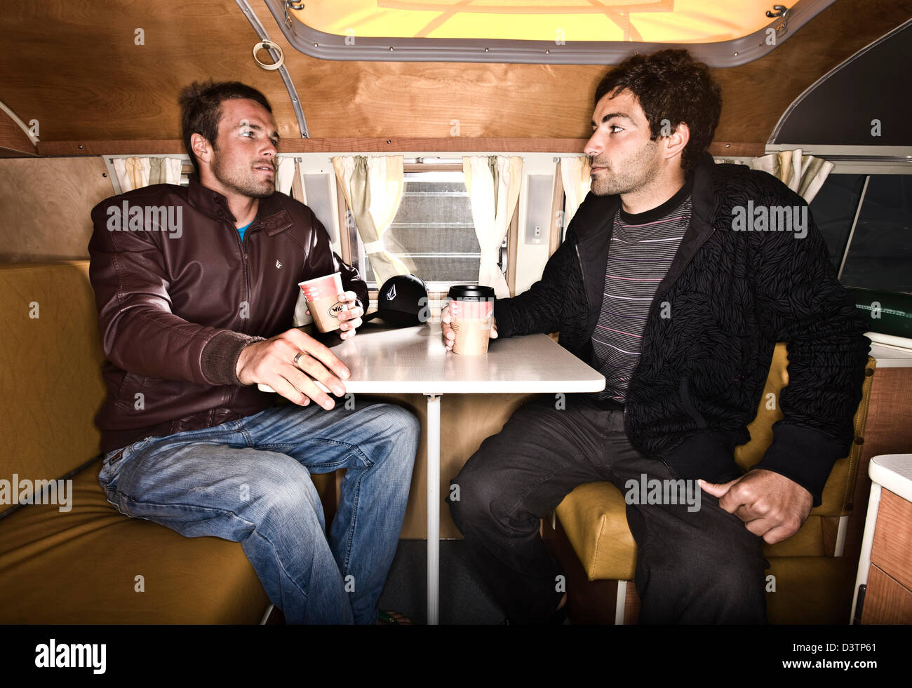 Due surfisti sedersi a tavola in VW camper, Sant Agnese, Cornwall, Regno Unito Foto Stock