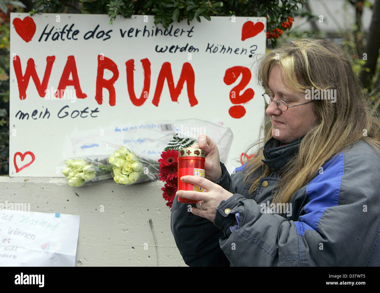 Sabine Bucker accende una candela di fronte ad una lettura del segno "Perché?" per esprimere solidarietà con le vittime dell'amok eseguire presso il Geschwister Scholl scuola in Emsdetten, Germania, Mercoledì, 22 novembre 2006. Un ex allievo stormed il suo ex scuola il lunedì le riprese in modo casuale, ferendo 37 persone prima di uccidere se stesso. Foto: Bernd Thissen Foto Stock