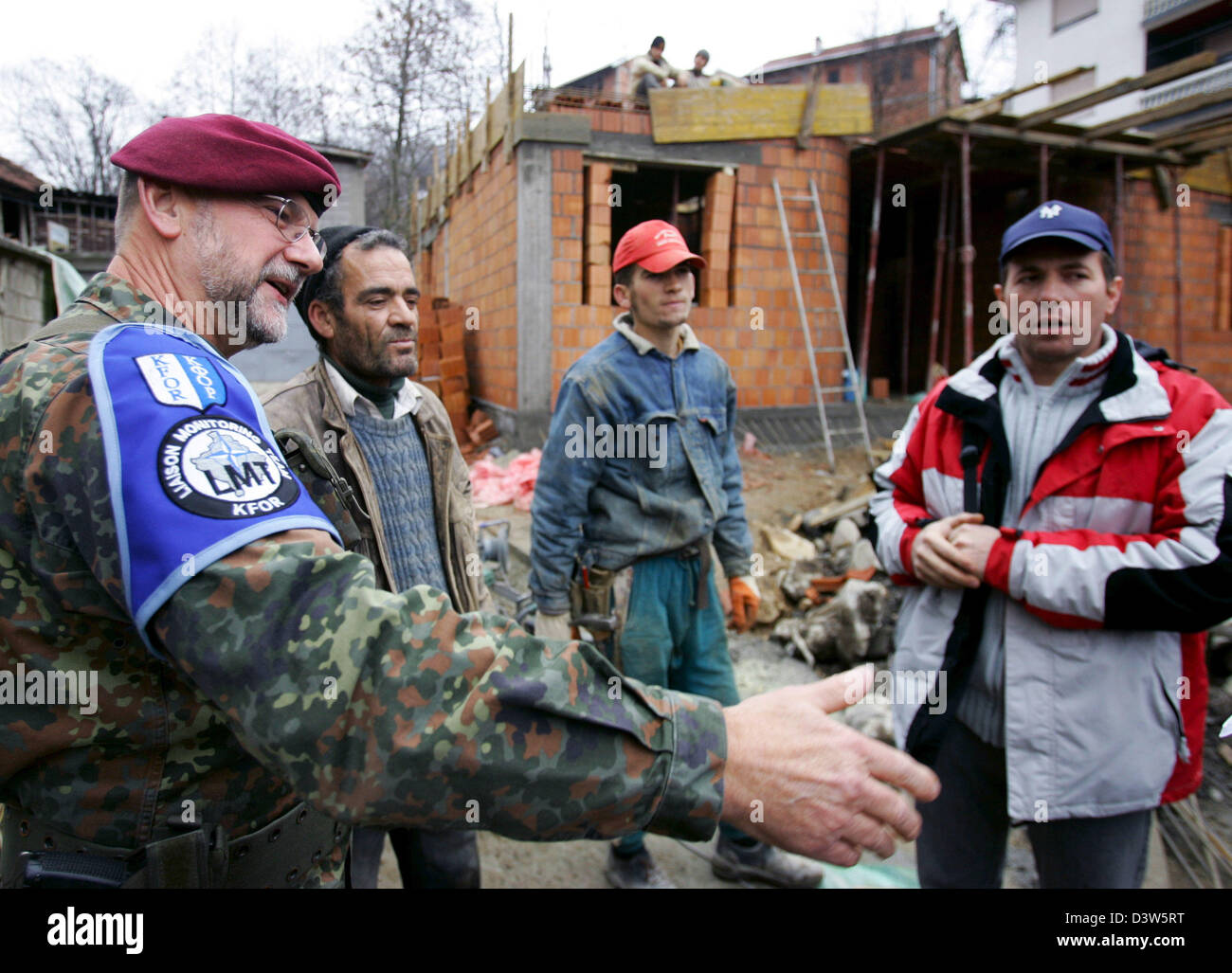 Forze armate tedesche giustificano Officer Classe I Detlef Kerkow (L) del Liaison Team di monitoraggio (LMT) parla con lavoratori edili in Mushnikovo, Kosovo, 13 dicembre 2006. Il villaggio si trova a nord di Prizren è uno dei molti villaggi pattugliato da LMT che si prende cura dei residenti" questioni. Foto: Matthias Schrader Foto Stock