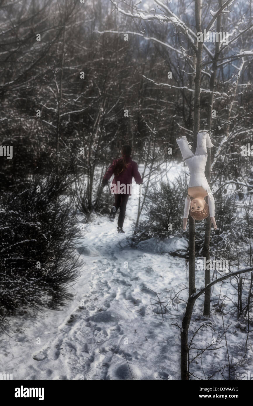 Un inquietante bambola è appeso a un albero, una ragazza è in esecuzione di distanza Foto Stock