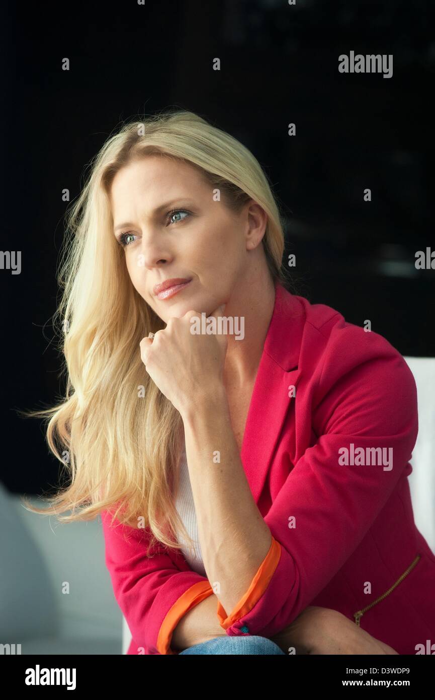 Vita donna seduta su una sedia laterale ad angolo di appoggio per il mento sulla mano fisted pensieroso gomito poggiato sul ginocchio Foto Stock