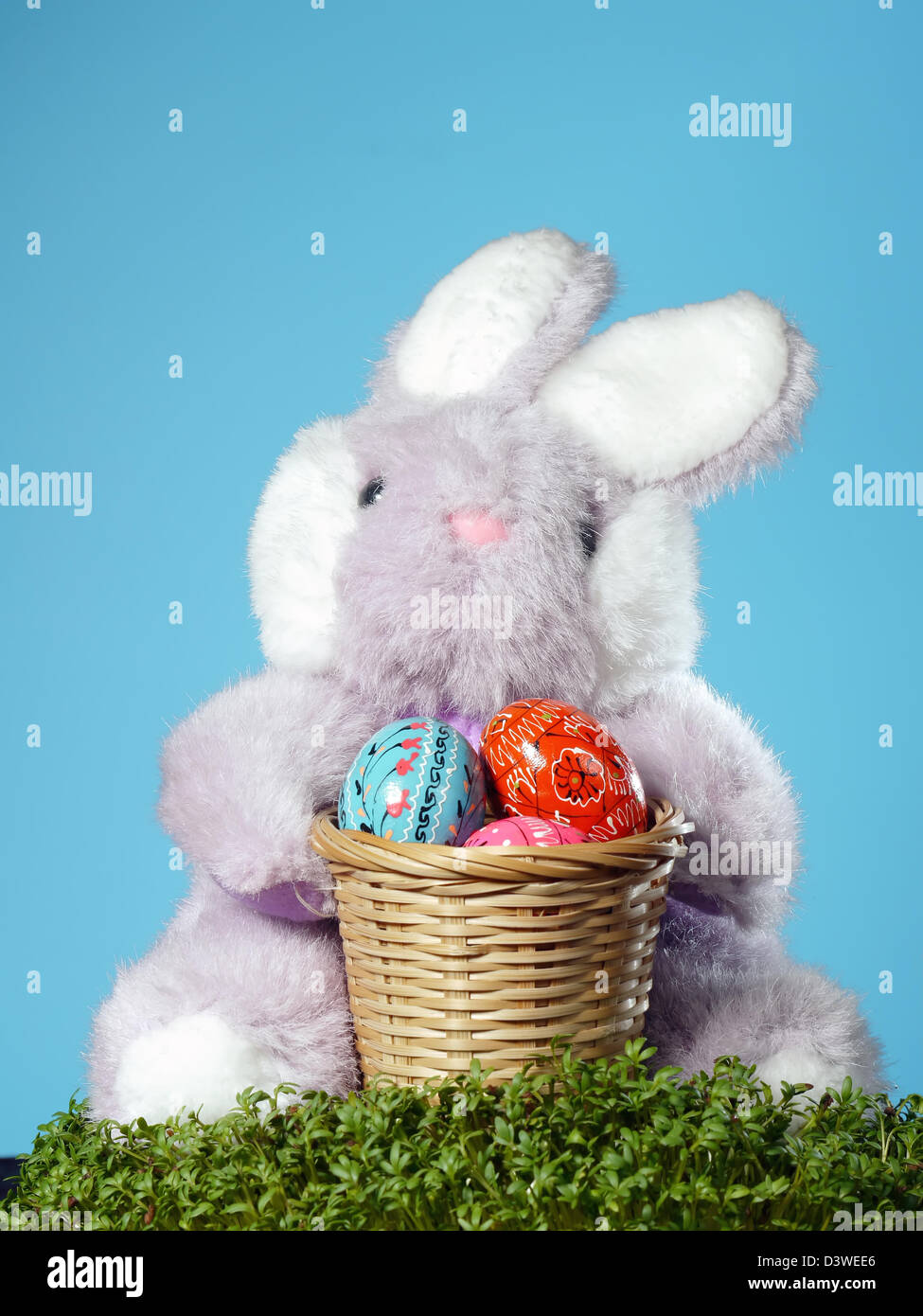 Coniglietto di pasqua seduto con cesto in legno pieno di uova di pasqua nel crescione Foto Stock