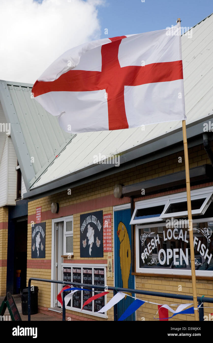 Il St George's Cross bandiera di Inghilterra volare al di fuori di un mercato del pesce in Sussex. Foto Stock