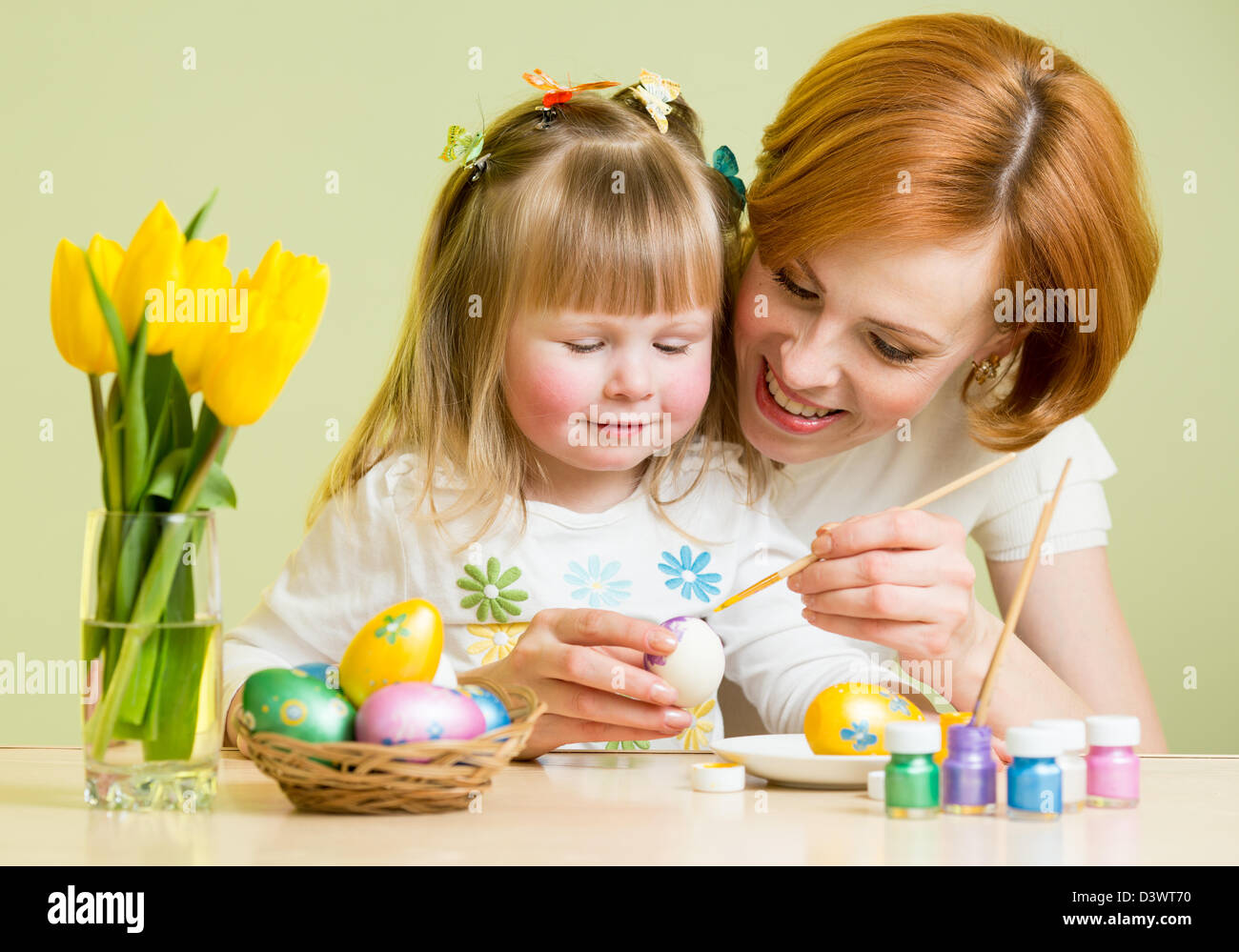 Felice madre figlia insegna a dipingere le uova di pasqua Foto Stock