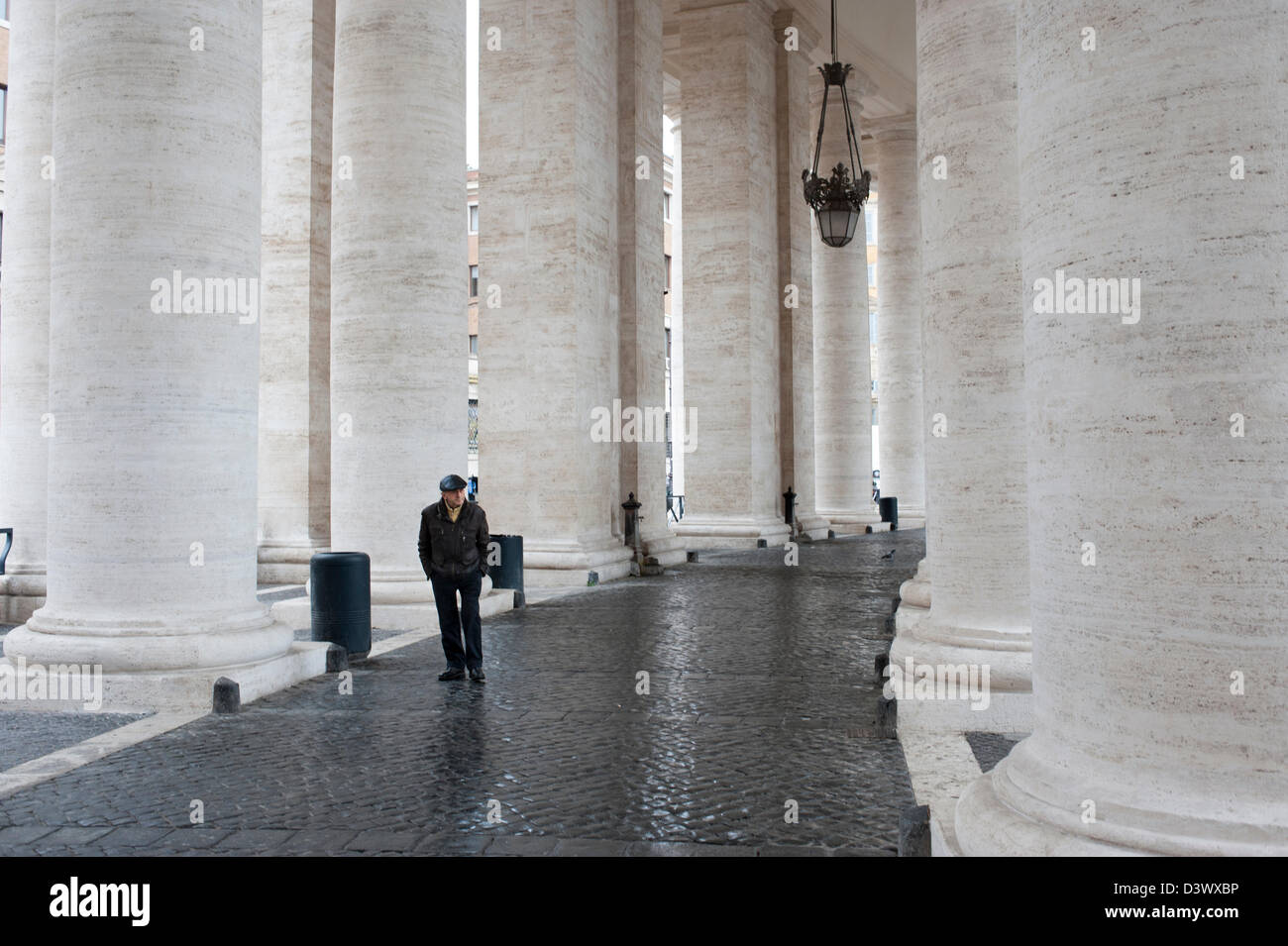 L'uomo cammina nel colonnato di Piazza San Pietro. Foto Stock