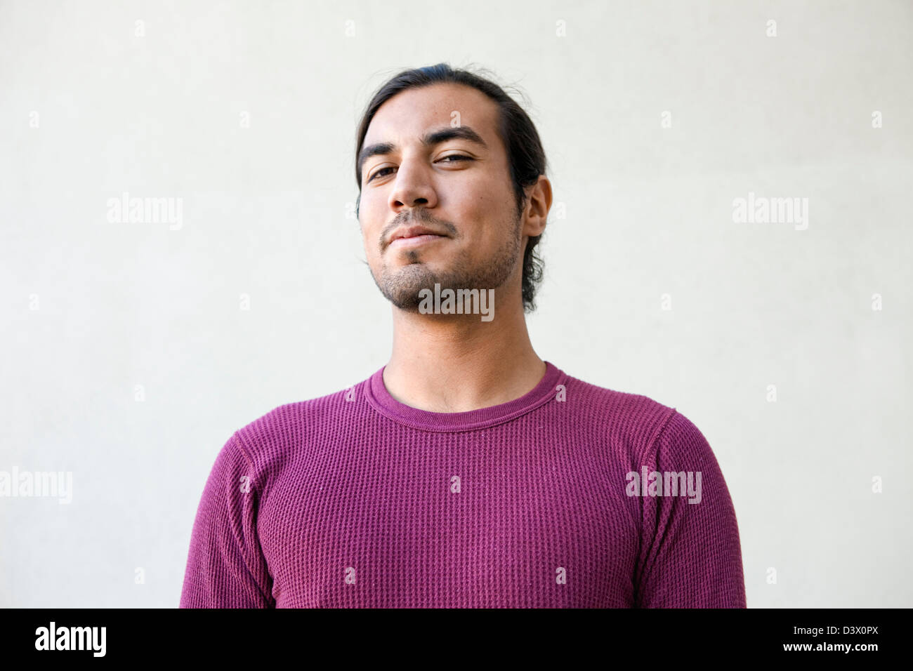 Ritratto di giovane adulto con i capelli lunghi messicano-american maschio con espressione di semi-sorriso, dubbio e giocosità Foto Stock