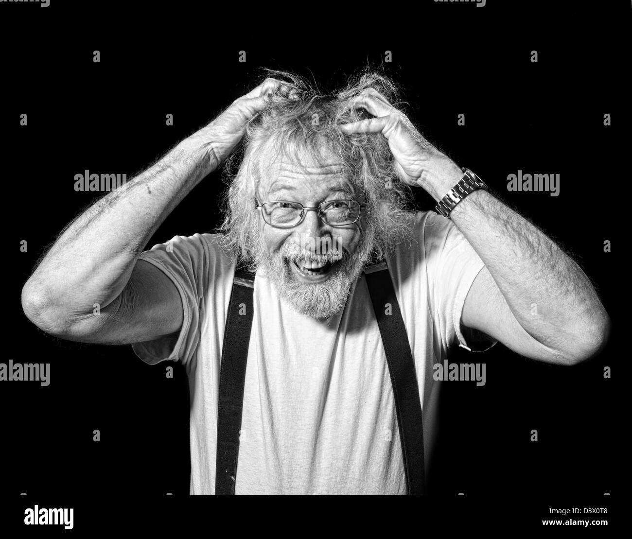 Monocromatico di Senior con un look impazzita sul suo viso e mani afferrando i suoi capelli isolato su nero Foto Stock