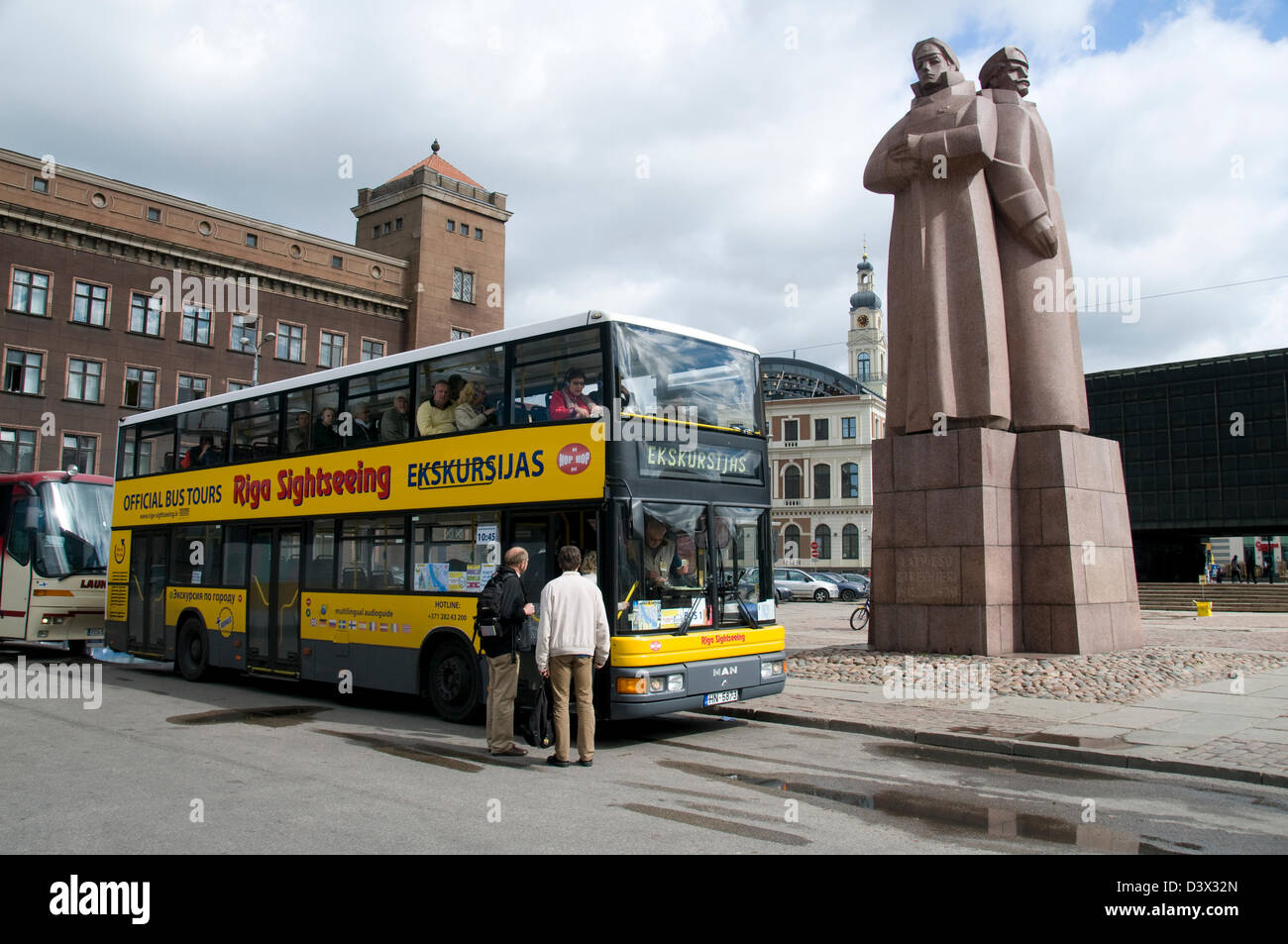 I turisti che si imbarcaranno su un autobus turistico di riga accanto al monumento sovietico dei riflemen rossi lettoni a riga, Lettonia, Stati baltici Foto Stock