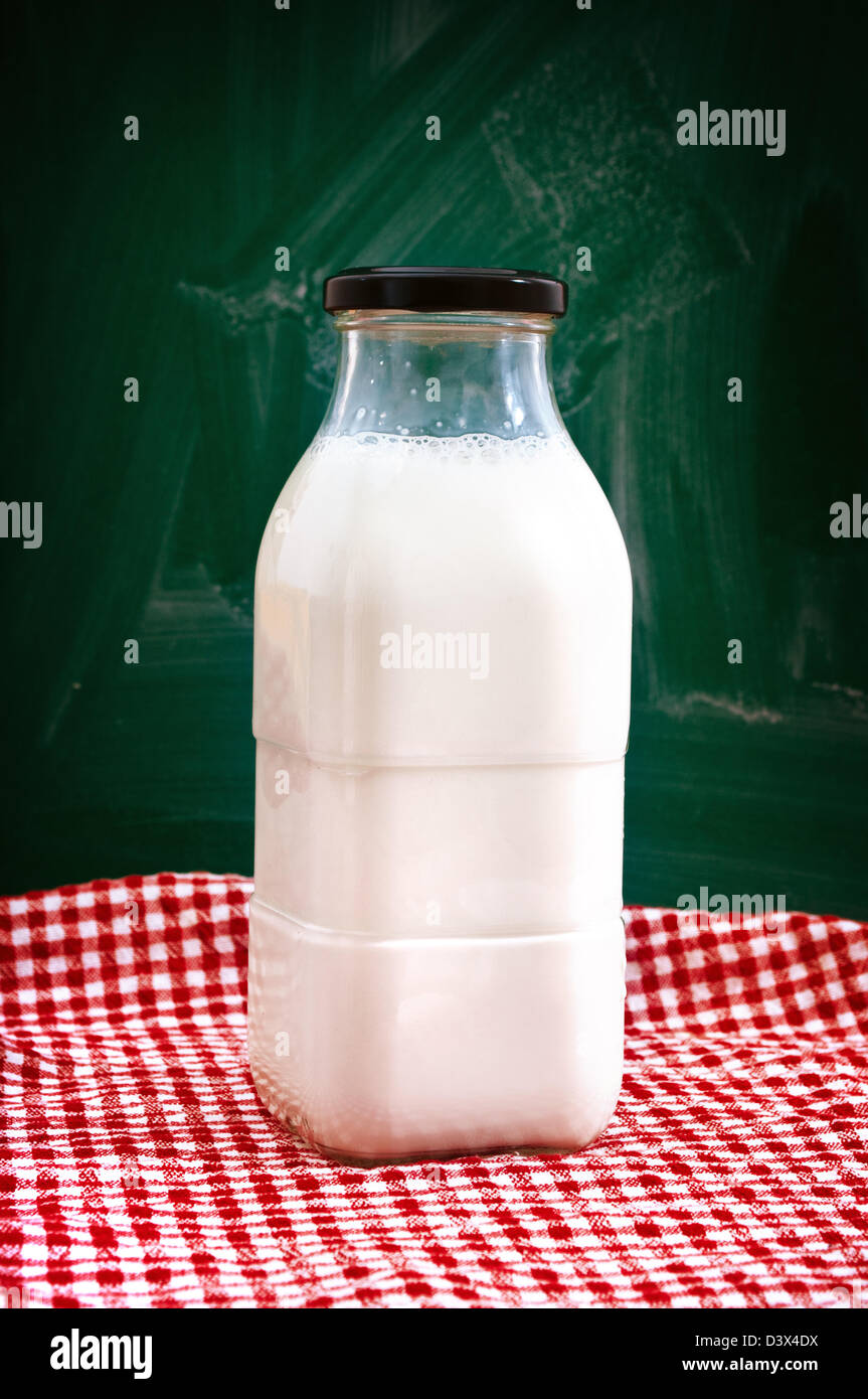 Bottiglia di latte su un tavolo da cucina con rosso e tovaglie bianche. Foto Stock