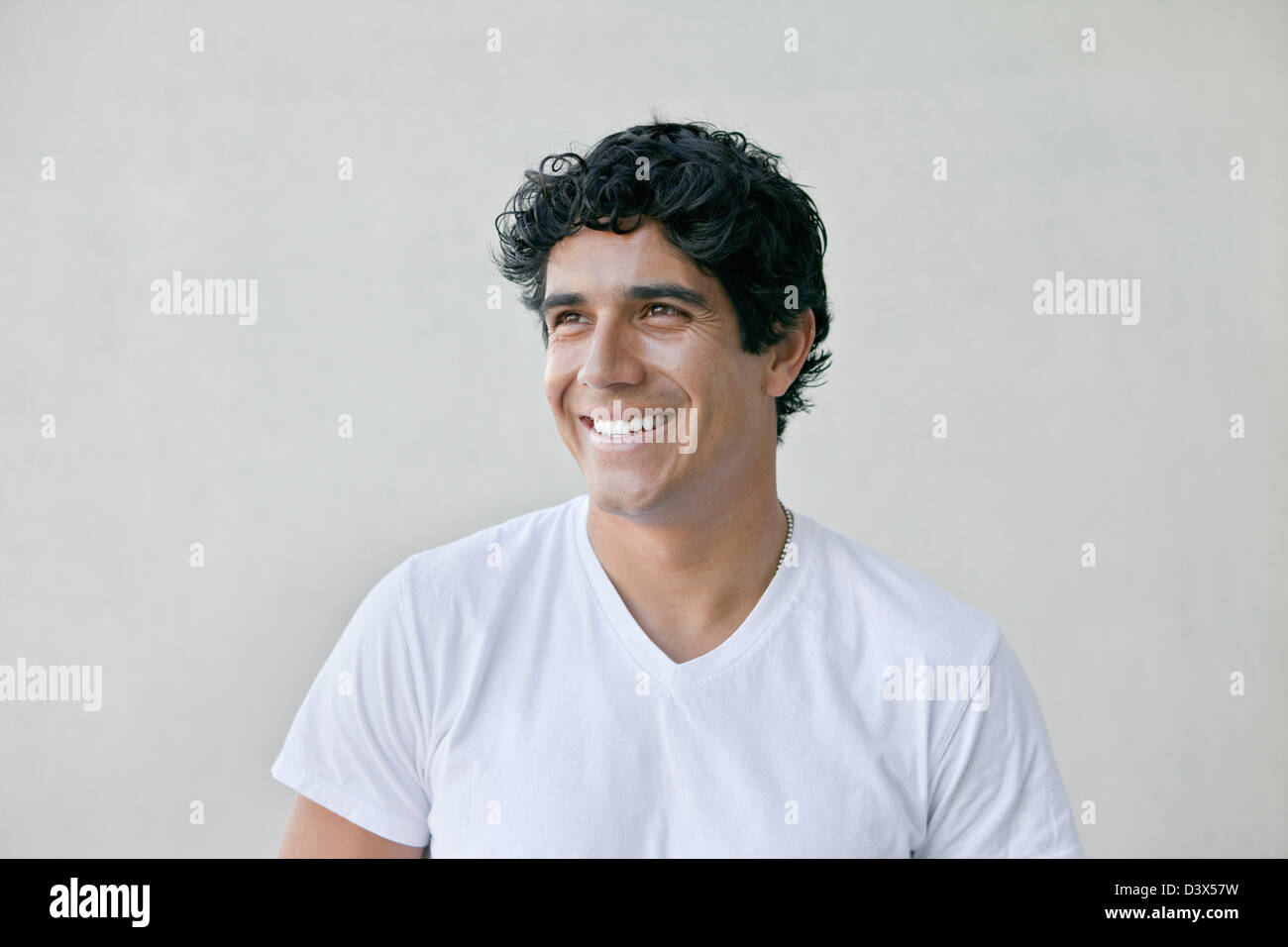 Sorridente Ritratto di giovane adulto messicano-americana indossa maschio bianco semplice t-shirt e khakis Foto Stock