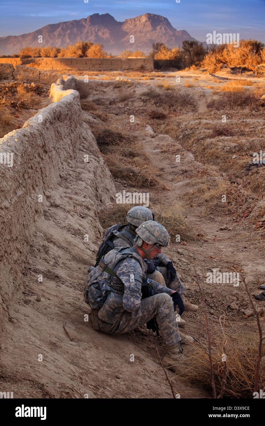 Soldati americani di attendere per un improvvisato dispositivo esplosivo (IED) per essere reso sicuro prima di proseguire con la loro missione. Foto Stock