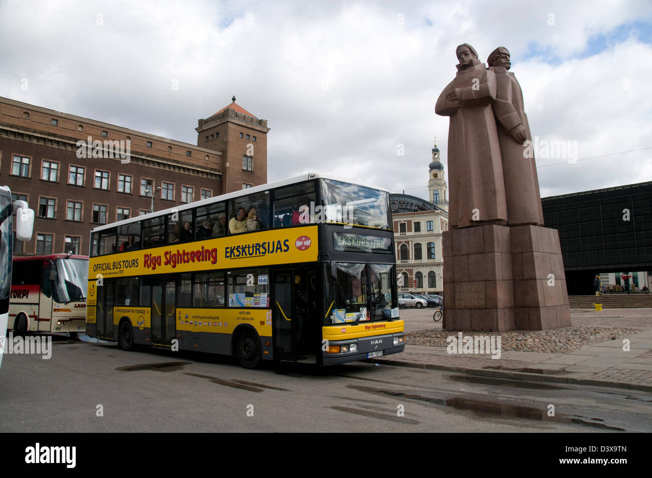 I turisti che si imbarcaranno su un autobus turistico di riga accanto al monumento sovietico dei riflemen rossi lettoni a riga, Lettonia, Stati baltici Foto Stock