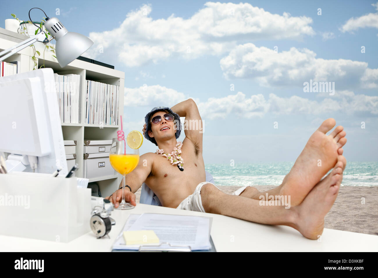 Giovane uomo al lavoro fantasticando su beach, cocktail e vita facile Foto Stock