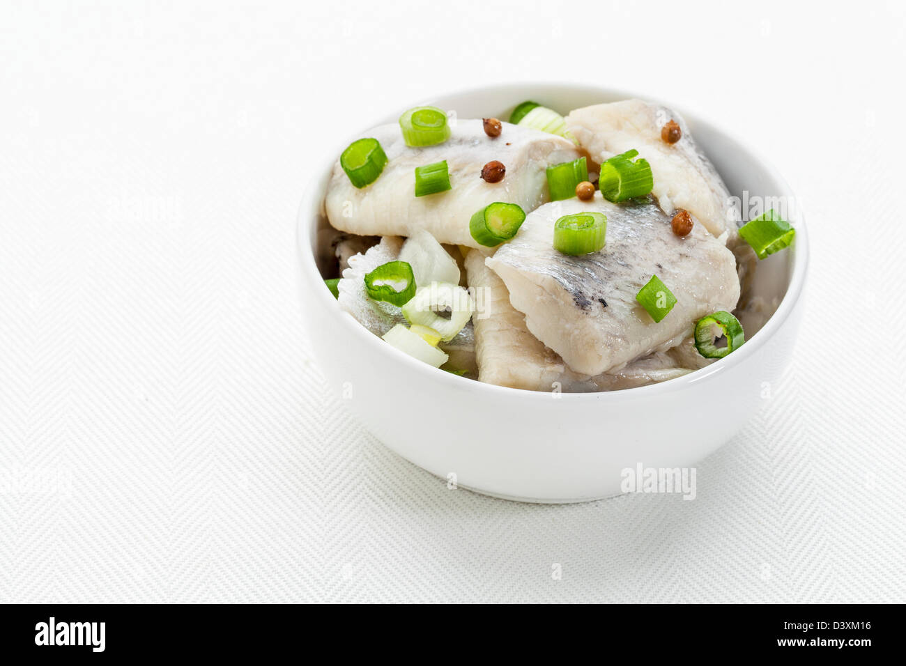 Aringhe nel vino, con cipolla verde e spezie - salsa bianca piatto sulla tovaglia Foto Stock