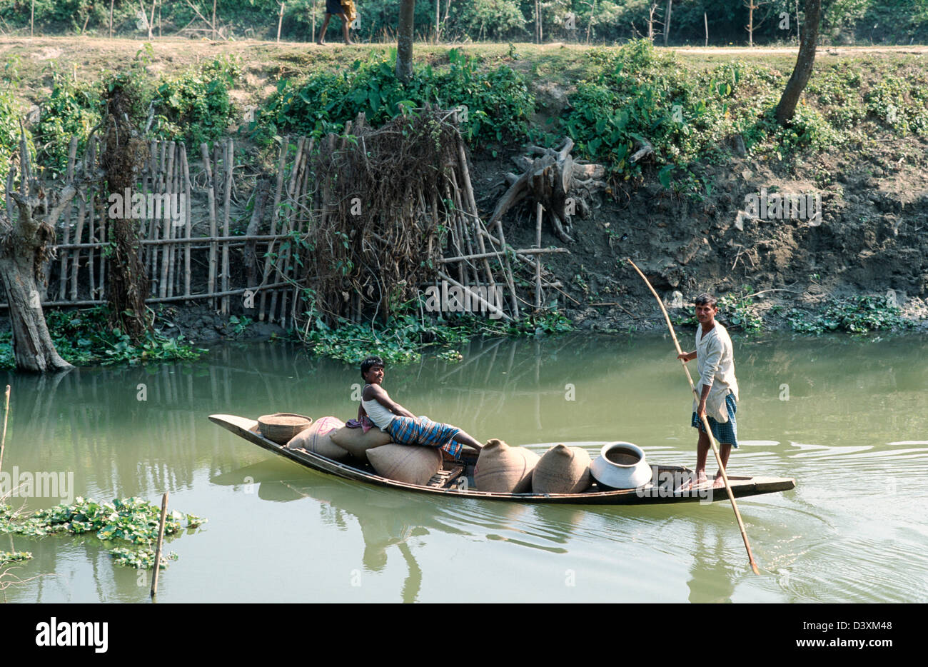 Punzonare una barca carica di sacchi di riso e fornisce downriver ad un villaggio remoto. Vicino Rajoir, Bangladesh. Foto Stock