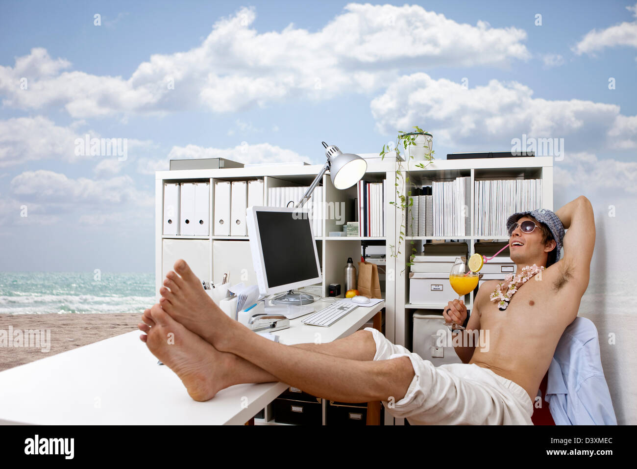 Giovane uomo al lavoro fantasticando su beach, cocktail, vita facile Foto Stock