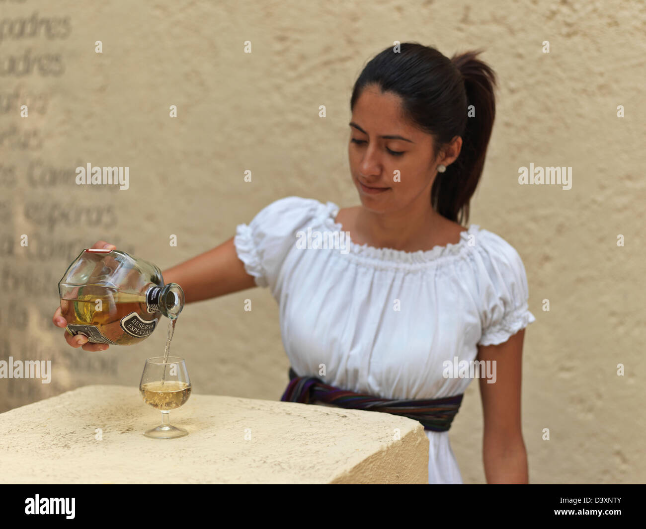 Messico Jalisco Tequila, giovane donna messicana in abito tradizionale versando la tequila in un bicchiere Foto Stock