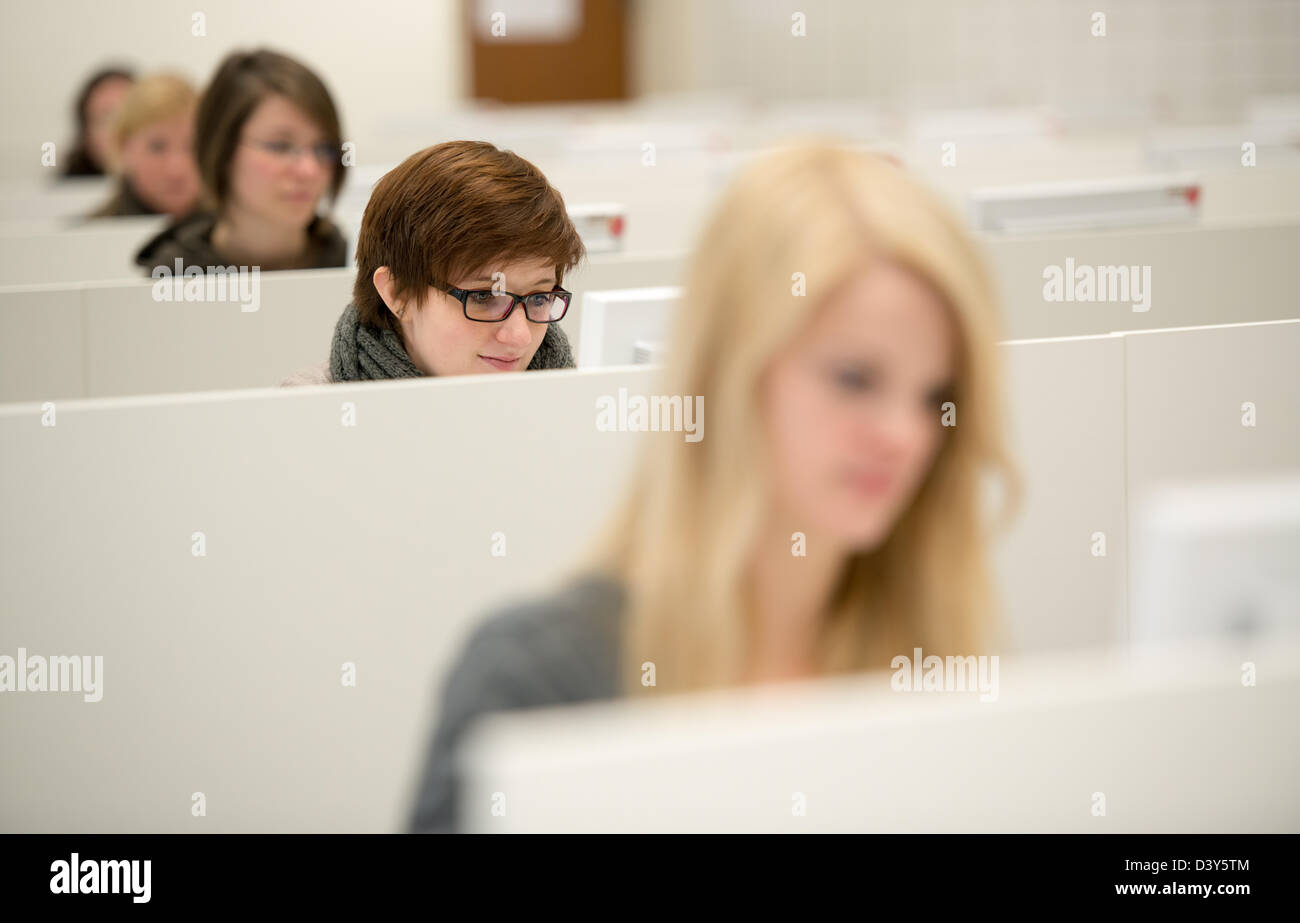 Brunet ragazza funziona con computer desktop, altre ragazze sfocato funzionano con computer troppo Foto Stock