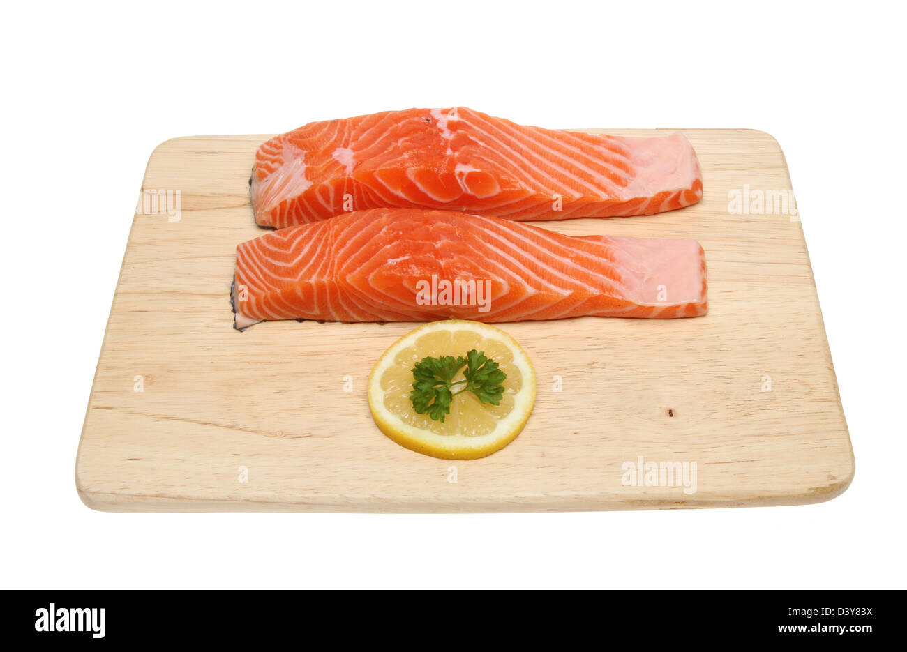 Due materie filetti di salmone con una fettina di limone e prezzemolo su una tavola di legno isolata contro bianco Foto Stock