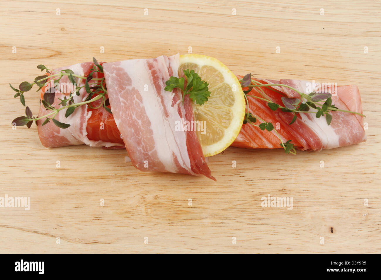 Bistecca di salmone avvolto in pancetta con limone e timo su una tavola di legno Foto Stock