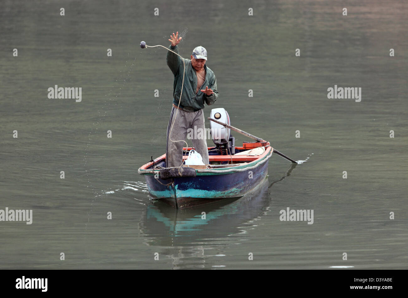 Hong Kong, Cina, uomo getta la pesca un galleggiante in acqua Foto Stock