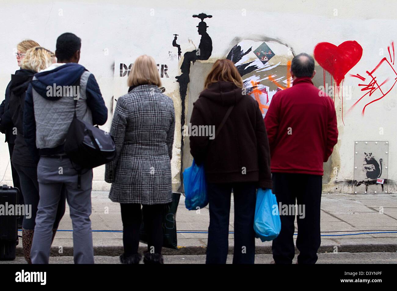 Londra, Regno Unito. Il 25 febbraio 2013. Persone gethered intorno alla banksy rubato arte da poundland negozio di parete a Londra oggi, come graffiti artist Banksy arte è stato ritirato dalla vendita all'asta dopo una campagna da Londra residenti a recuperarlo, murale che era discutibilmente strappato dalla parete di un North London shop. Credito: fuat akyuz / Alamy Live News Foto Stock