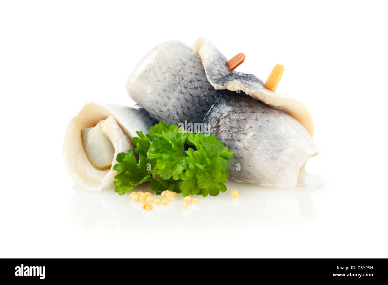 Rollmops tedesco - kipper avvolto intorno al cetriolo sottaceto, guarnite con prezzemolo e semi di senape, su sfondo bianco Foto Stock